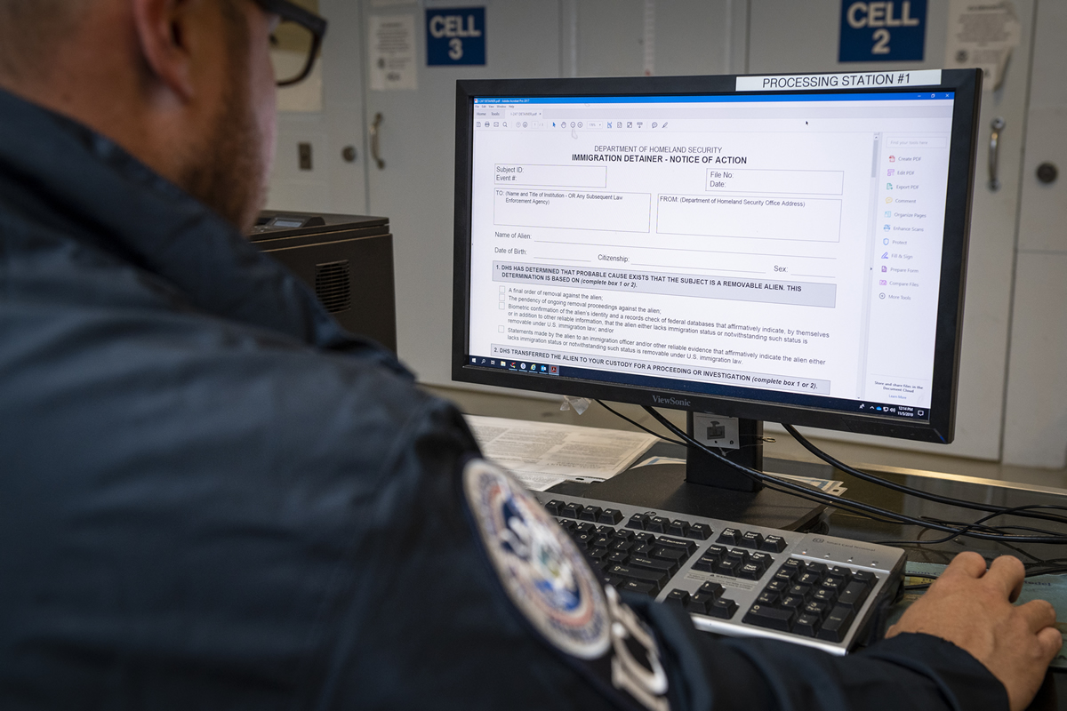 ICE Officer at computer, looking at detainer form