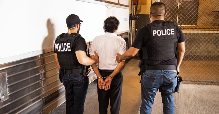 2 officers escorting an individual in handcuffs