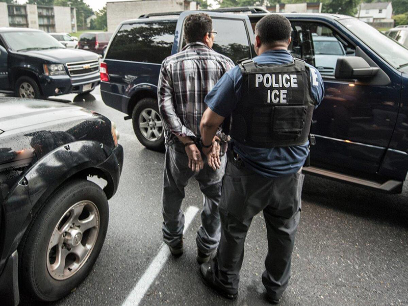 An individual in a plaid shirt being handcuffed by an officer