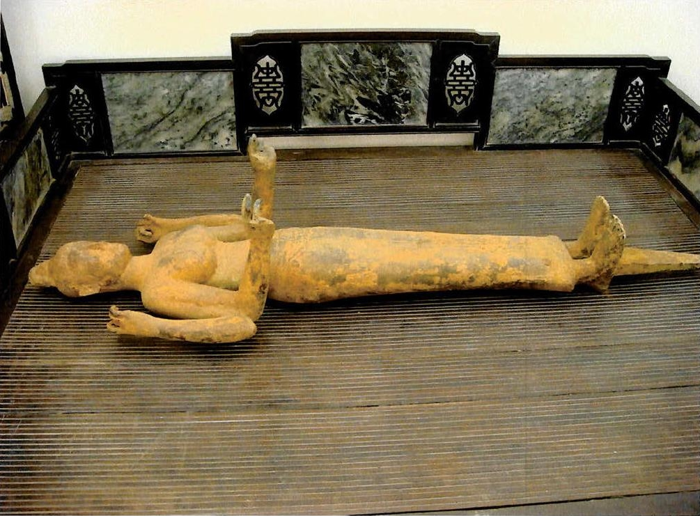  photograph of the Durga statue lying on its back, covered in what appears to be dirt and minerals indicative of recent excavation