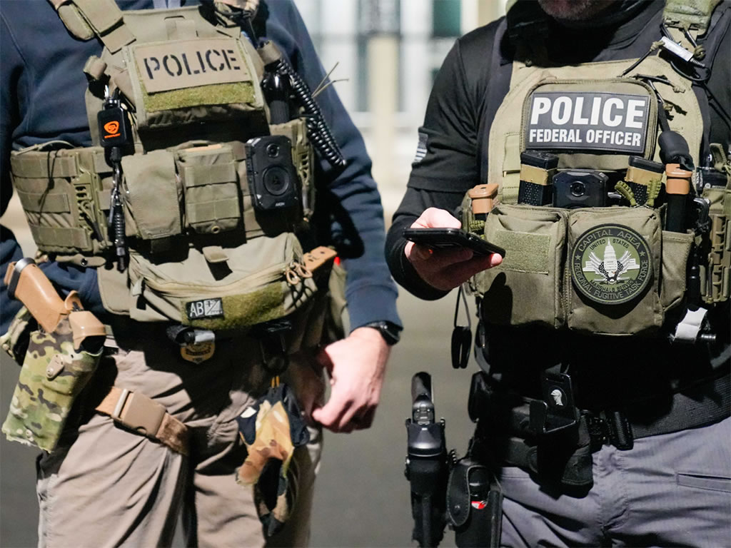 Two federal law enforcement officers coordinate with other officials on the ground during an enhanced immigration enforcement operation near Washington, D.C. Feb. 4.