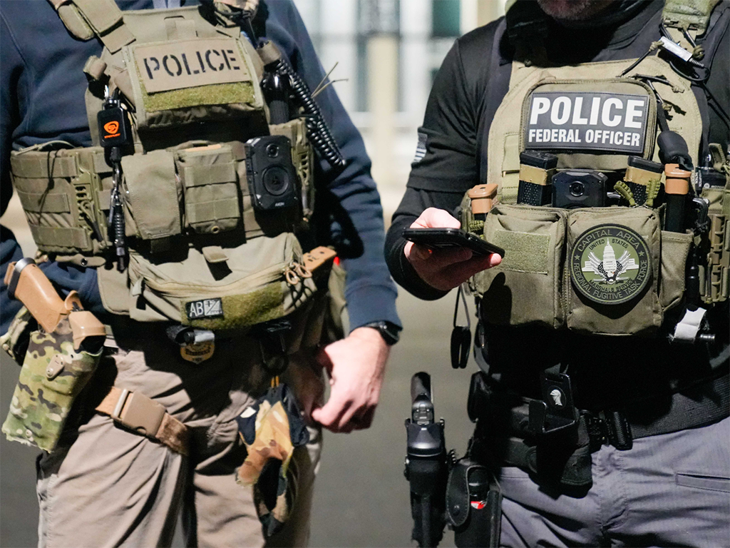 Two federal law enforcement officers coordinate with other officials on the ground during an enhanced immigration enforcement operation near Washington, D.C. Feb. 4.