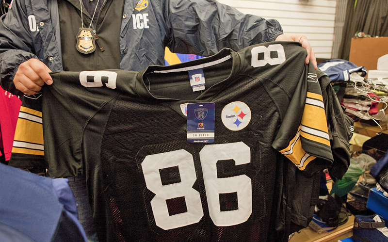 ICE agent holds up one of the confiscated fake jerseys