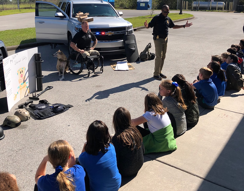 HSI Tampa Special Agent Alvis Lockhart and Computer Forensic Analyst Justin Gaertner and his service dog Gunner presented to Tampa Bay area children during the Great AmericanTeach-In