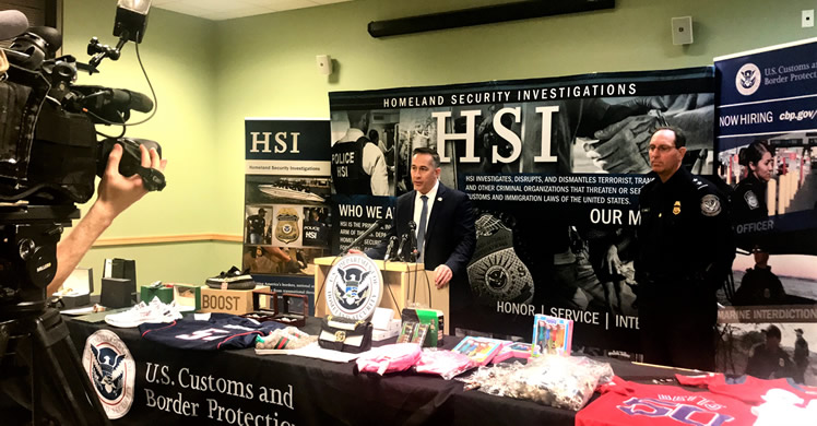 Homeland Security Investigations (HSI) Boston acting Special Agent in Charge Jason Molina and Customs and Border Protection Director of Field Operations, Boston Michael Denning highlight the risks of purchasing counterfeit property items, in front of recently-seized items . 