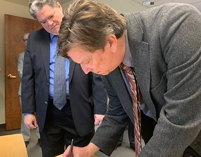 HSI Providence Special Agent Michael Polouski looks on as Haffenreffer Museum official signs documentation officially receiving possession of artifacts.